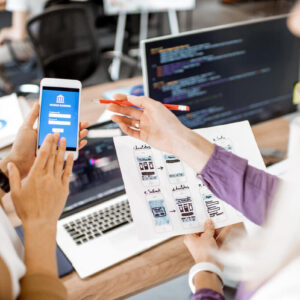 Developing mobile application Developers or web designers developing mobile application for banking in the office, close-up on phone and paper sketches